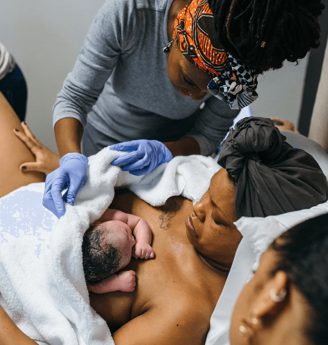 A midwife's hands supporting a mother holding her newborn